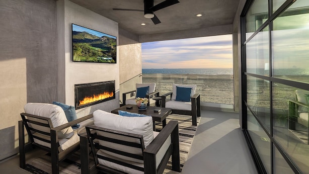 Una sala de estar moderna con chimenea, asientos cómodos y un ventanal con vistas a la playa.