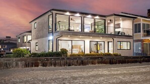 Una casa moderna de dos pisos con amplios ventanales, un balcón y una valla de madera al frente.