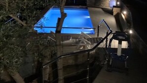 A swimming pool with a blue tint, surrounded by a fence and trees. - Superb sea view apartment with private pool! 5 minutes from the center of Roses. (Roses)
