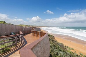 A wooden boardwalk leading to a beach with waves crashing onto the shore. - Logans Beach Apartments - The Loft (Warrnambool)