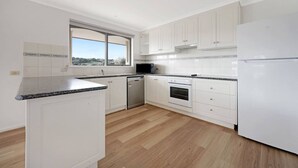 Een moderne keuken met witte kasten, een inbouwoven en een vaatwasser.