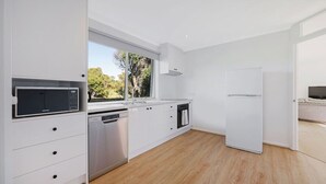 A modern kitchen with white cabinetry, stainless steel appliances, a dishwasher, and a built-in oven.