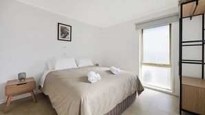A modern bedroom with a bed, bedside table, and a window.