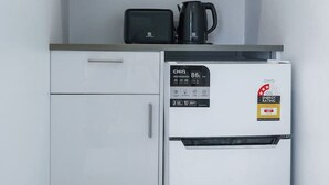 A compact kitchenette with a microwave, toaster, and refrigerator. - Logans Beach Apartments - Lil Greenviews (Warrnambool)