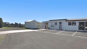 A building with a parking lot, a covered area, and a small shed. - Logans Beach Apartments - Lil Greenviews (Warrnambool)