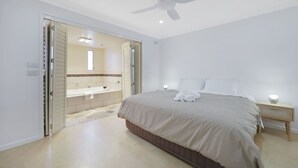 Une chambre à coucher avec un lit, une table de chevet et une salle de bain équipée d’une baignoire et d’un miroir.