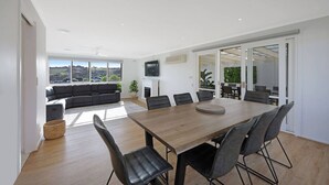 Un salon moderne avec un grand canapé, une table à manger avec des chaises et une cheminée.