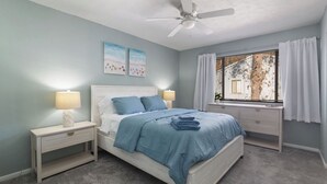 A bedroom with a bed, two bedside tables, a ceiling fan, and a window with curtains. - Modern & Stylish Condo Near UF - Foxmoor (Gainesville)