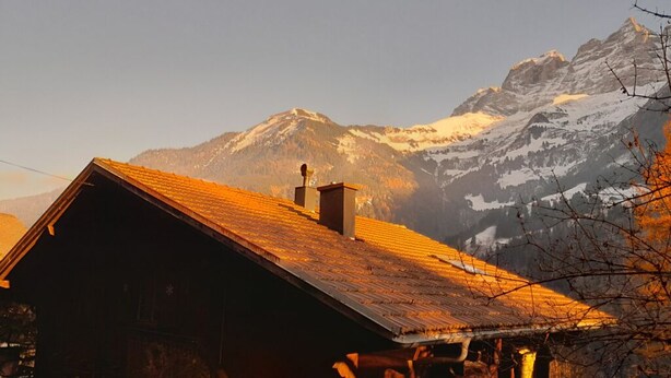 A wooden chalet with a sloped roof and a chimney, set against a backdrop of snow-capped mountains. - Champéry (CH) winter/summer, confort apart. 4-5p. in wooden chalet, superb view! (Champéry)