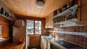 A compact kitchen with wooden cabinets, a tiled backsplash, and a window providing natural light. - Champéry (CH) winter/summer, confort apart. 4-5p. in wooden chalet, superb view! (Champéry)