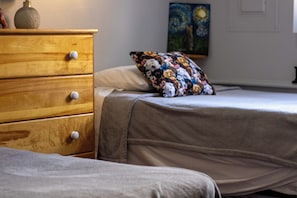 Un dormitorio con un aparador de madera, una cama con un cojín floral y un cuadro en la pared.