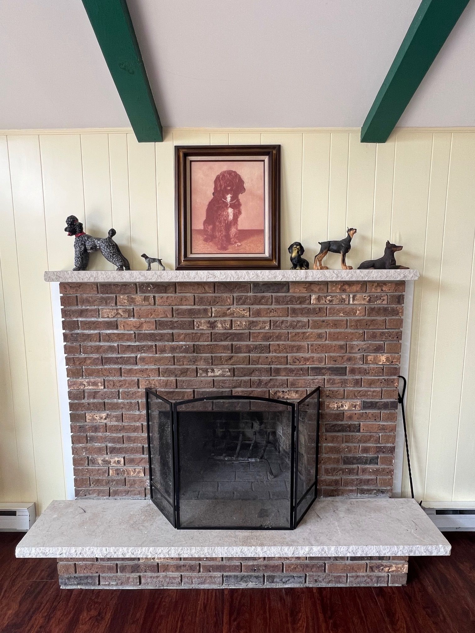 A fireplace with a brick surround, a mantel with framed artwork and dog figurines, and a white mantelpiece.