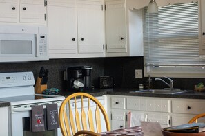 A kitchen with white cabinets, a microwave, a coffee maker, and a sink. - Mohawk - Fenced Yard Chalet (Sciota)