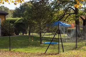 Un espacio exterior cercado con un trampolín y un toldo azul.