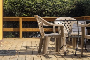 A wooden deck with two plastic chairs and a table.