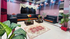 A modern living room with black sofas, a patterned rug, and decorative plants. - Hotel Aranna Residential Bandarban (Bandarban)