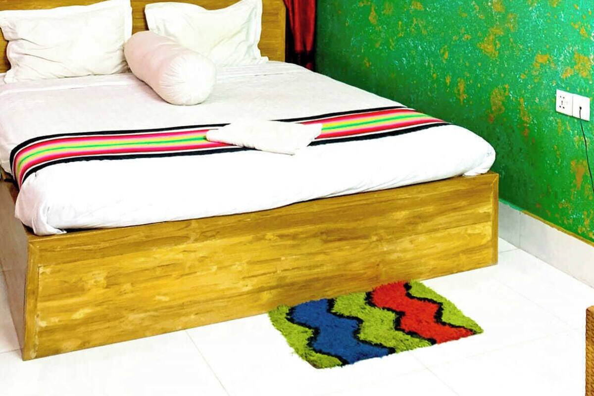 Une chambre à coucher avec un lit, un ventilateur de plafond, un climatiseur, un rideau rouge et un mur vert.
