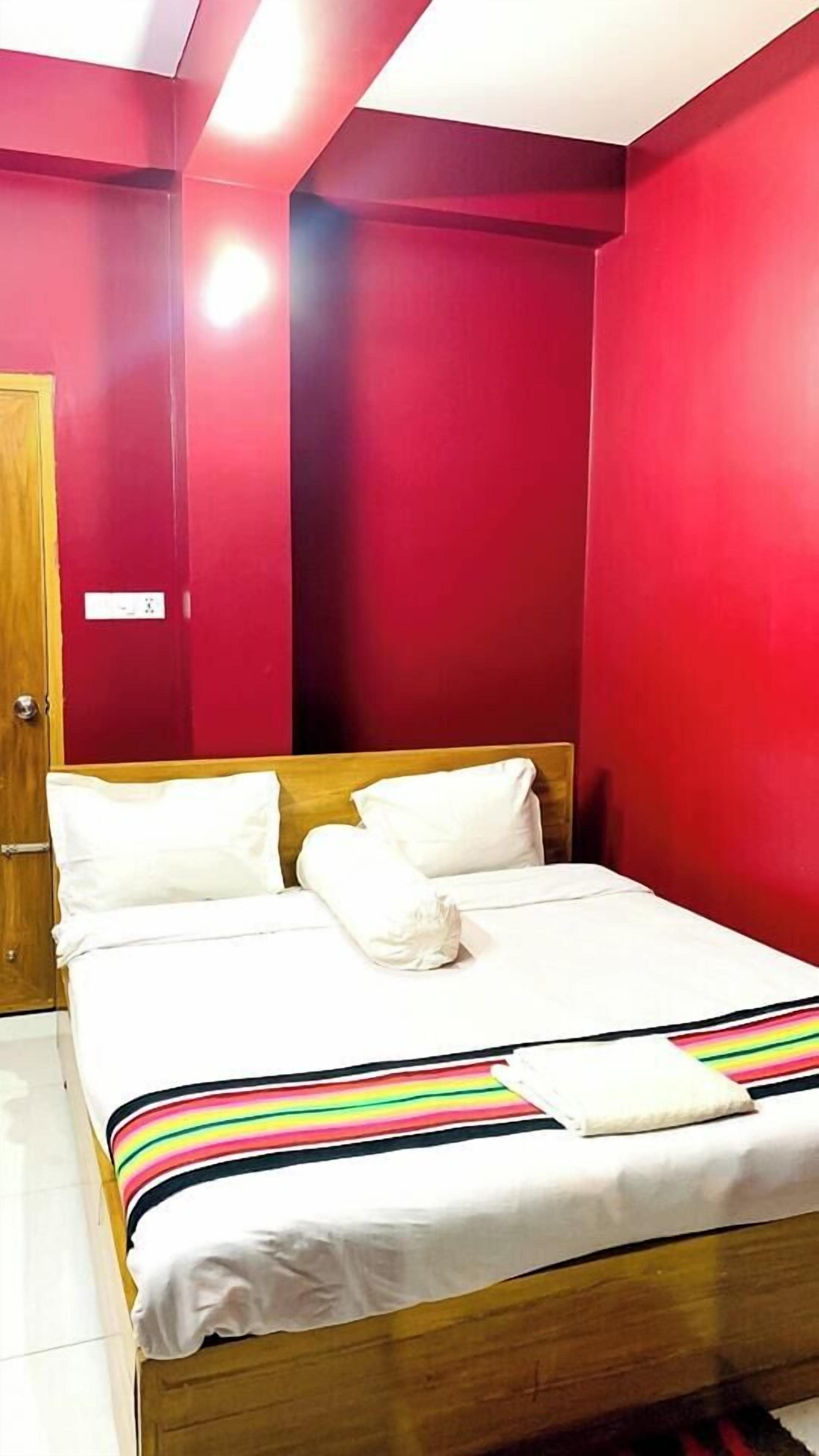 A room with a bed, red walls, and a wooden door.