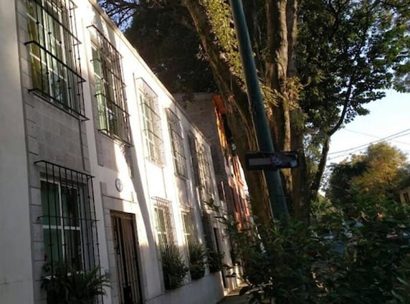 Um edifício com grades nas janelas, uma placa de rua e árvores ao redor.