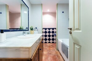 Casa de banho com duas pias, espelho, porta-toalhas e zona de duche.