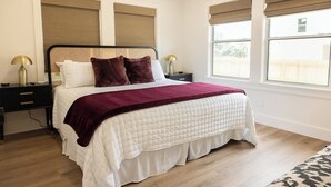 A neatly arranged bedroom with a bed, bedside tables, and a window with blinds. - College Station • Pickleball • 2mi Kyle Field (Bryan)