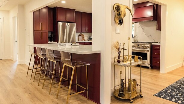 A modern kitchen with dark wood cabinets, a stainless steel refrigerator, and a unique skull decoration on the wall. - College Station • Pickleball • 2mi Kyle Field (Bryan)