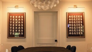 A conference room with a round table, chairs, and two framed signs on the walls. - College Station • Pickleball • 2mi Kyle Field (Bryan)