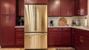 A kitchen with dark red cabinets, a stainless steel refrigerator, and a marble countertop. - College Station • Pickleball • 2mi Kyle Field (Bryan)