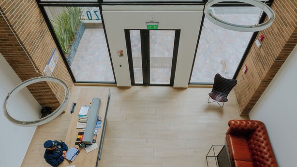 A reception area with a desk, a couch, and a door with an exit sign.