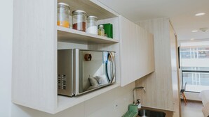A compact kitchen with built-in appliances, a small sink, and a window overlooking a balcony.