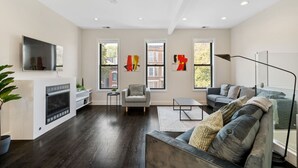 Una sala de estar moderna con chimenea, un sofá, un sillón y obras de arte en las paredes.