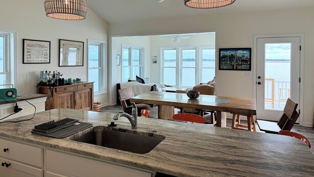 Una cocina moderna con una isla grande, luces colgantes y vistas al exterior.