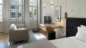 A modern hotel room with a bed, a desk, a chair, and a television. - Essência Portuense Studios (Porto)