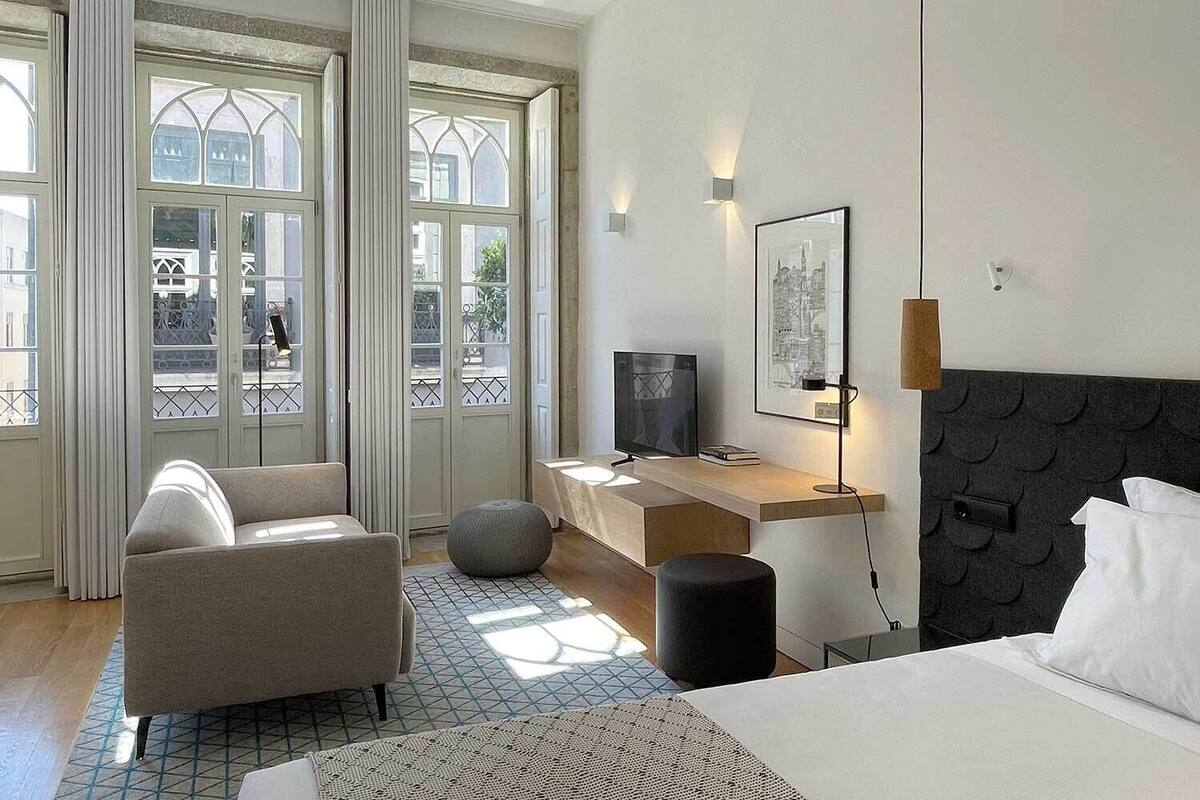 Et moderne hotelværelse med seng, skrivebord, stol og fjernsyn.