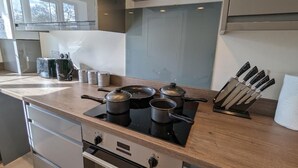 Een moderne keuken met een gasfornuis, pannen, een messenblok en een raam.