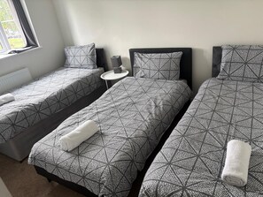 Une chambre d’hôtel avec deux lits simples, une petite table ronde et une fenêtre avec des rideaux.