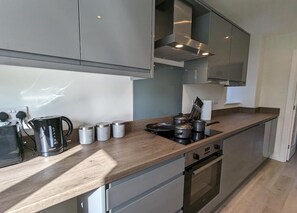 Eine moderne Küche mit Edelstahlgeräten, einer Holzarbeitsplatte und einem eingebauten Backofen.