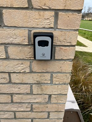 A stone wall with a black and gray intercom box labeled 'TTRWIN' mounted on it.
