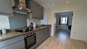A modern kitchen with stainless steel appliances, a wooden countertop, and a view into the dining area. - Watton House | 3 bedroom house with garden | Ipswich, London (Carbrooke)