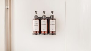 Three bottles of body wash, conditioner, and shampoo on a white cabinet.