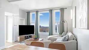 A modern living room with a flat-screen TV, a dining table, and a sofa.