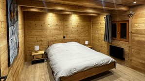 A wooden-paneled bedroom with a bed, bedside lamps, and a painting on the wall.