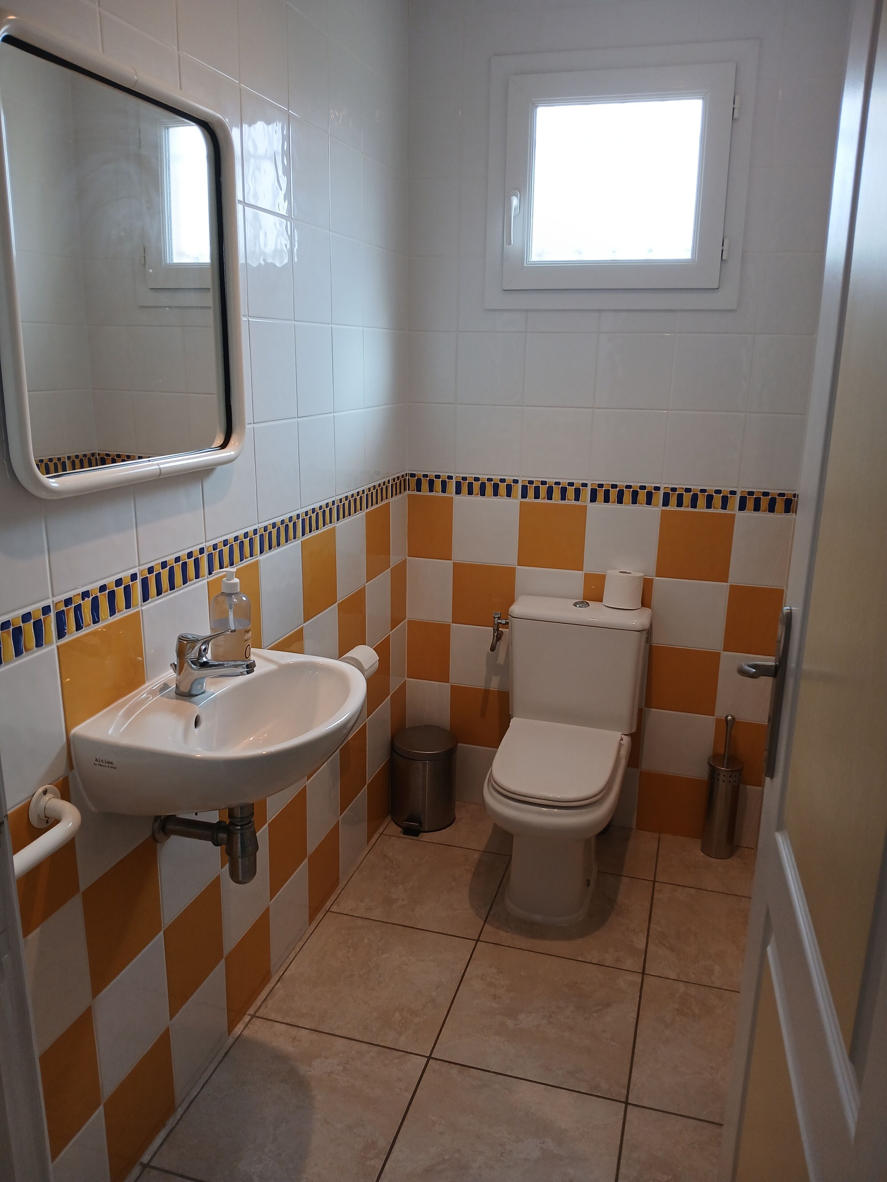 A bathroom with a sink, toilet, and window.