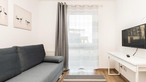 Una sala de estar moderna con un sofá gris, un escritorio blanco con un televisor y obras de arte en la pared.