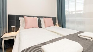 Una habitación de hotel con una cama grande, dos mesitas de noche y un ventanal con cortinas.