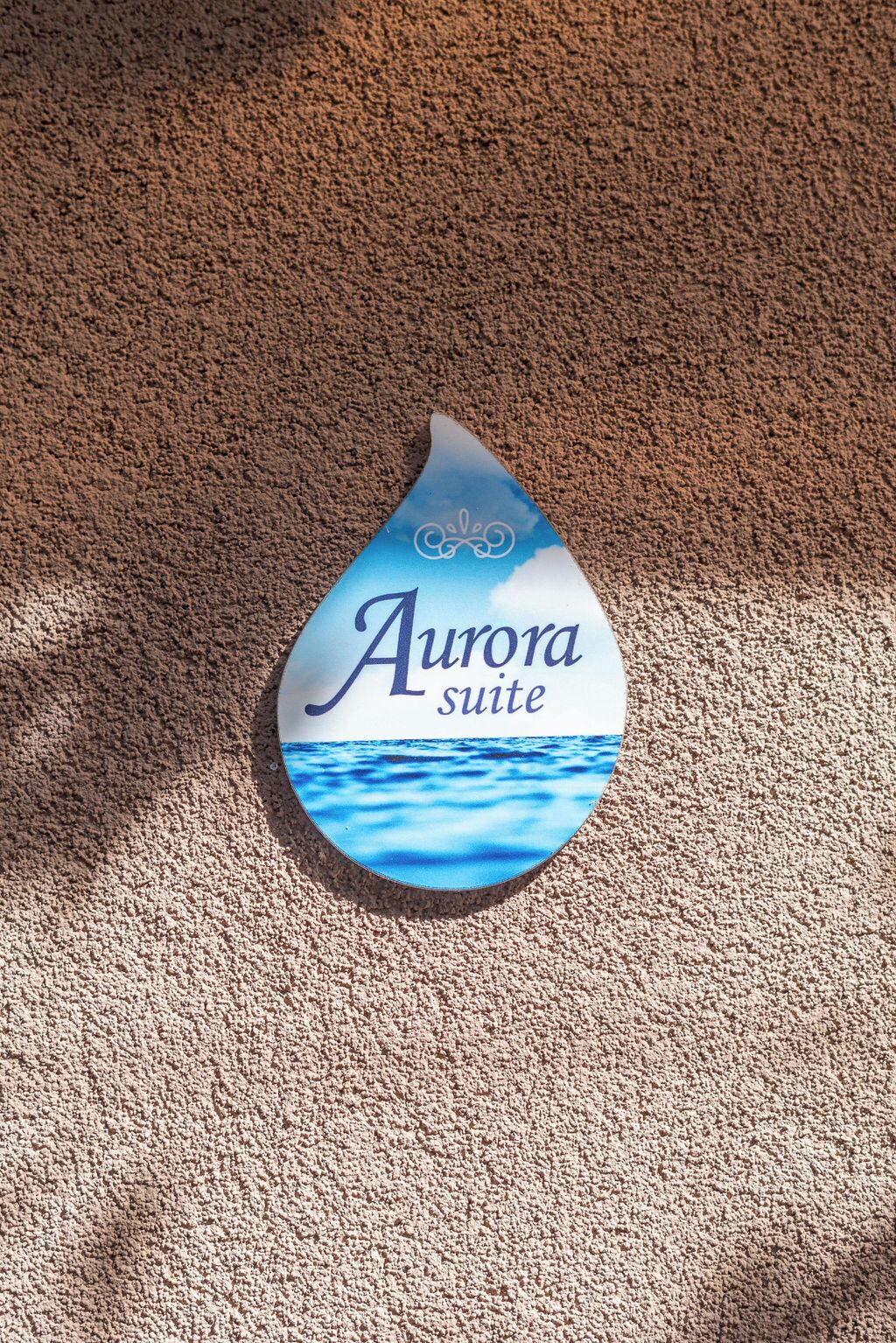 A sign with the text "Aurora suite" on a textured surface.