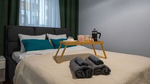 A neatly made bed with a wooden tray holding a coffee pot, cups, and a small cake. - Warsaw Airport Apt- Parking&Terrace - by Rentujemy (Warszawa)