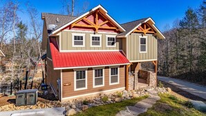 A two-story house with a red roof, wooden beams, and a stone foundation. - Luna Bear Lodge (Gatlinburg)