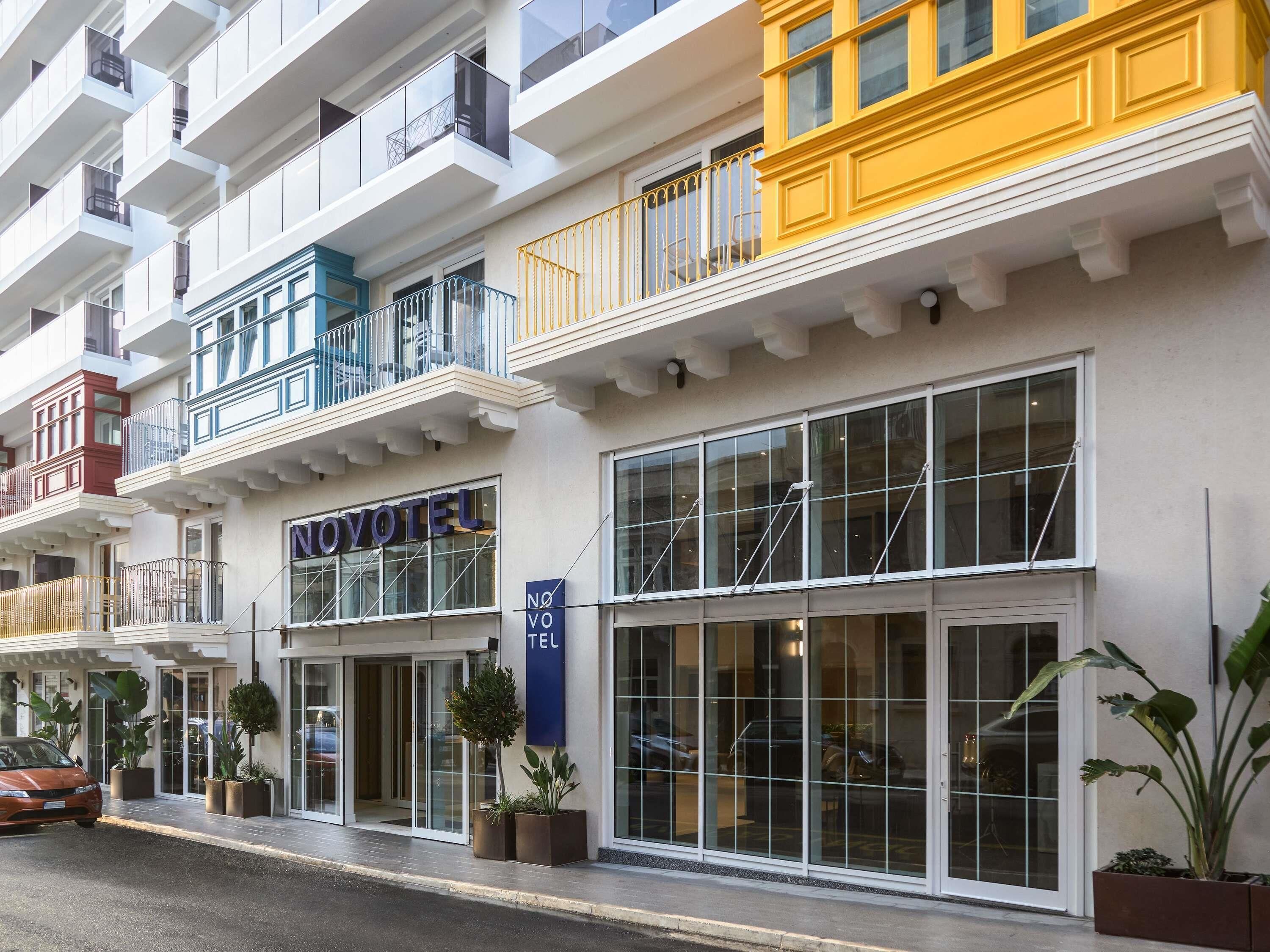 A hotel with multiple balconies, large windows, and a sign reading 'NOVOTEL'.