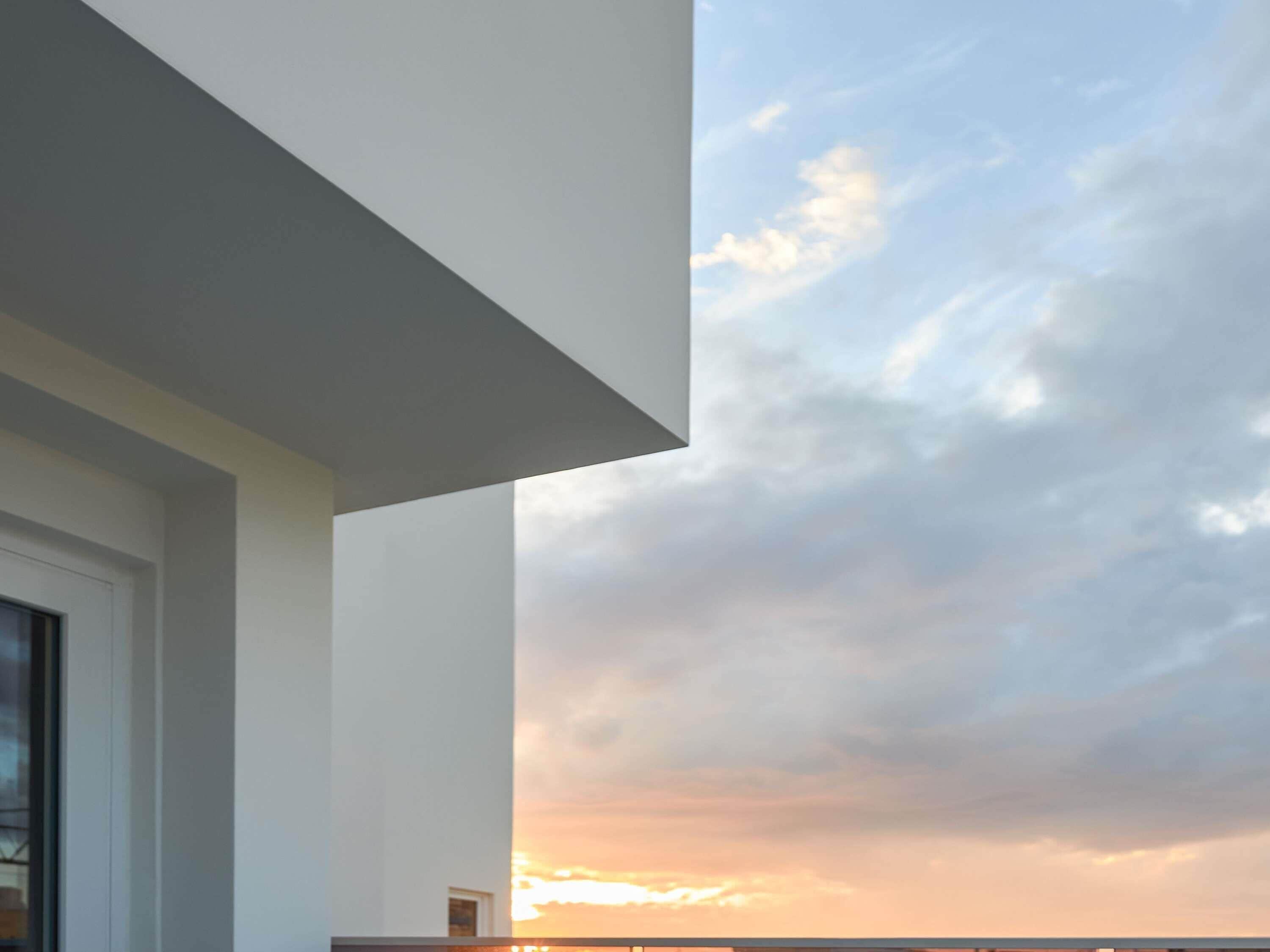 A modern building with a large glass window and a view of the sky.